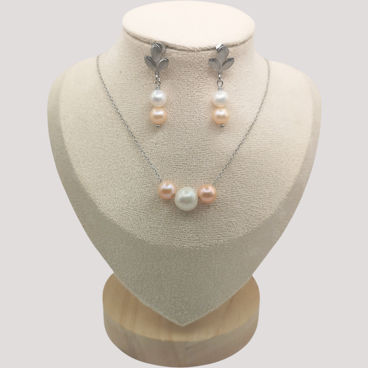 Pearl necklace and earrings set on a mannequin bust with a plain background