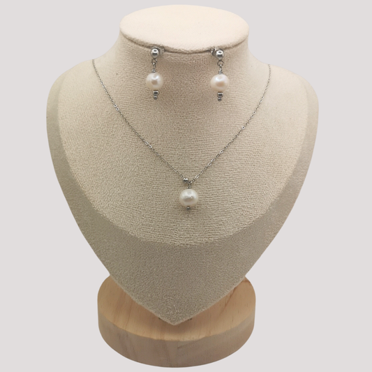 Pearl necklace and earrings on a mannequin bust with a plain background