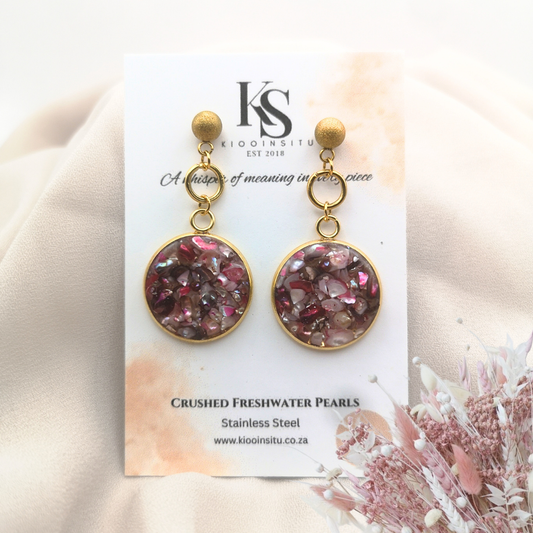 These luminous earrings feature crushed freshwater pearls, artfully set within 20 mm gold-plated stainless steel bezels and sealed under a clear, glass-like resin that captures every soft glimmer of light.