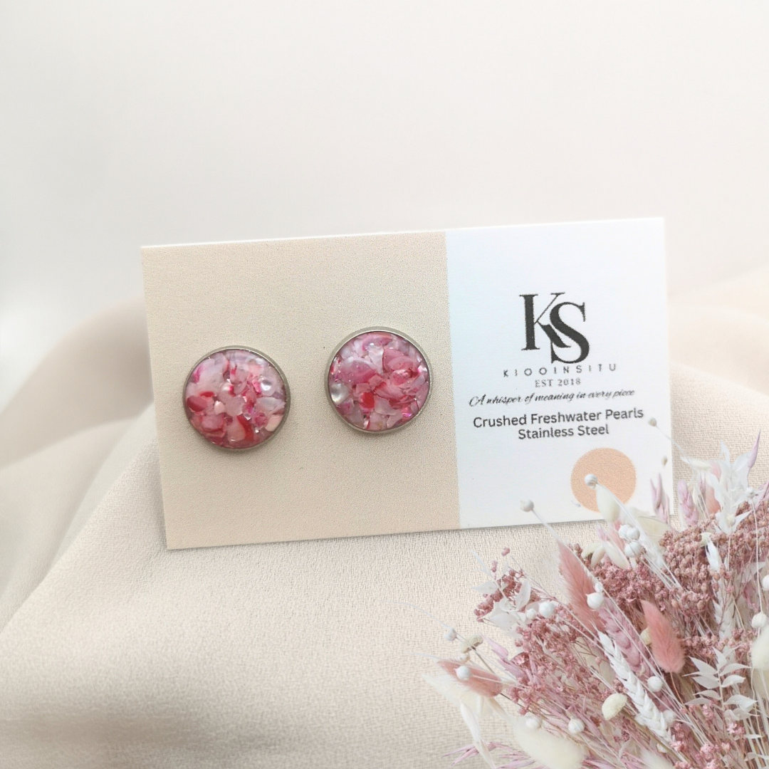 Handmade with care, these 12 mm stainless steel studs feature crushed freshwater pearls in pink tones, sealed beneath a glass-like resin that captures their gentle shimmer.