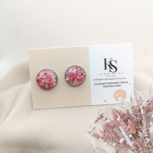 Handmade with care, these 12 mm stainless steel studs feature crushed freshwater pearls in pink tones, sealed beneath a glass-like resin that captures their gentle shimmer.