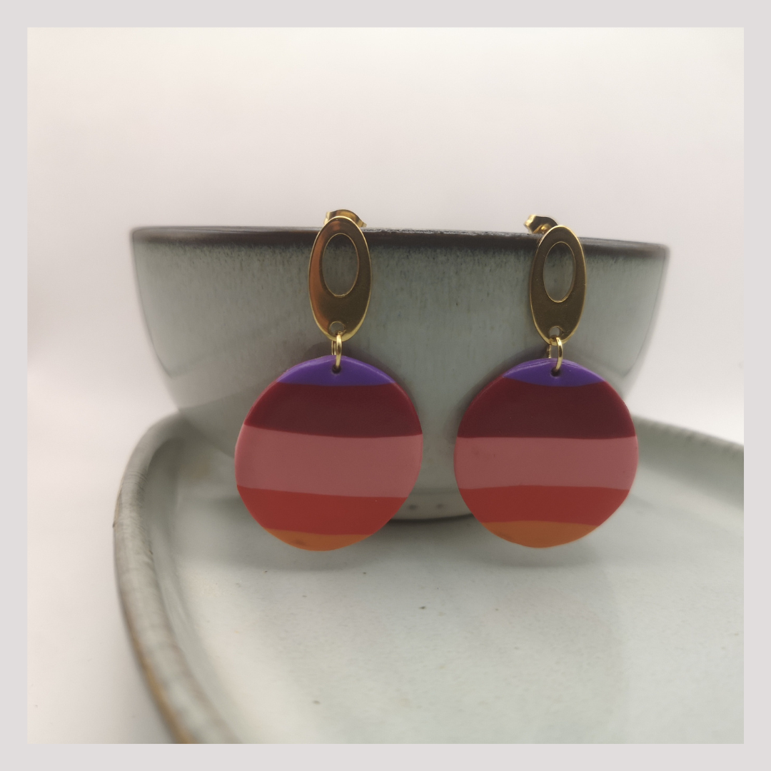 Colorful Polymer clay earrings hanging from a ceramic grey bowl.