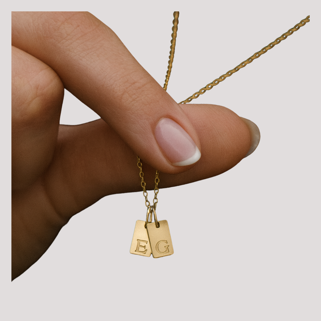 Gold plated personalised necklace with letters E and G held by a woman's hand