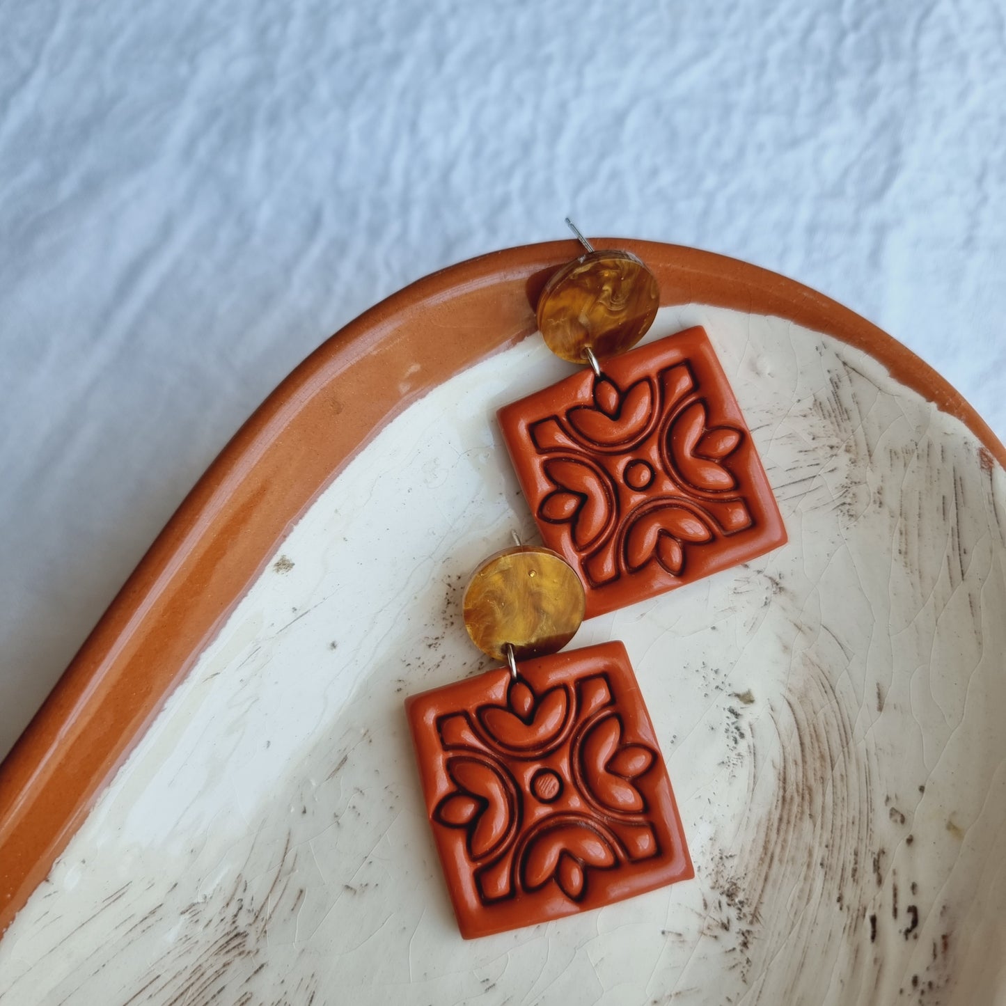 Handcrafted for a distinctive and stylish look. These eye-catching earrings feature vibrant Terracotta-colored polymer clay embossed squares