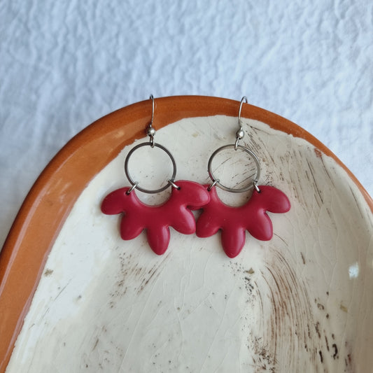 These handmade earrings feature a unique shape crafted from polymer clay in a beautiful maroon color. 