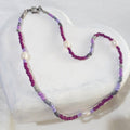 This handmade necklace pairs the luminous white of freshwater pearls with purple and grey glass beads