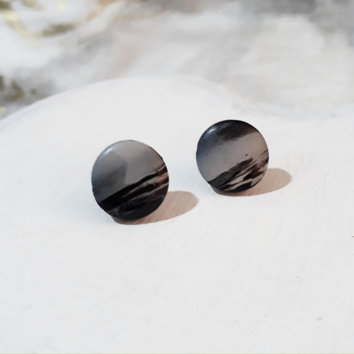 Round black and white marbled polymer clay stud earrings with glossy surfaces and contrasting flowing lines.