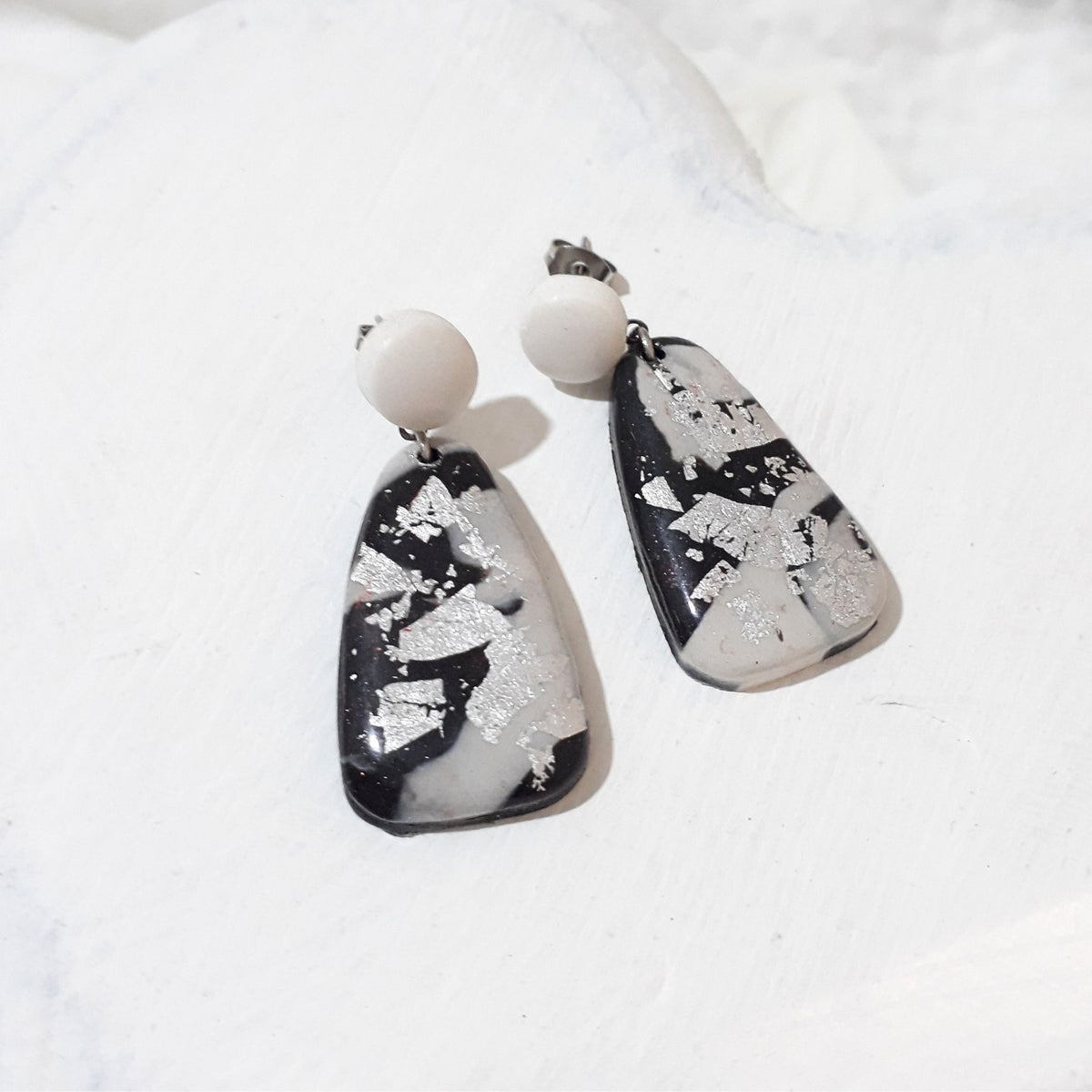 Polymer clay earrings with round white stud tops and tapered black and white drops decorated with silver-coloured flecks.