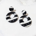 Black and white striped polymer clay earrings with round stud tops and glossy open circle drops.