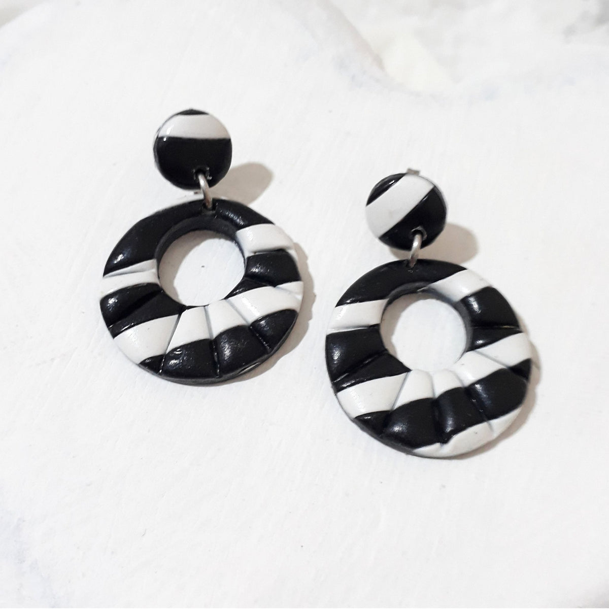 Black and white striped polymer clay earrings with round stud tops and glossy open circle drops.