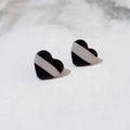 Black heart-shaped polymer clay stud earrings, each with a broad diagonal white stripe.