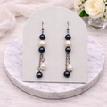 Pair of pearl earrings on a marble stand with a soft background