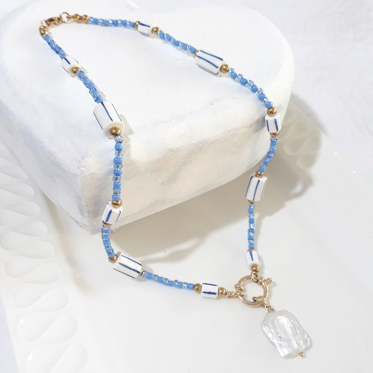 This handmade necklace brings together a white square baroque freshwater pearl, soft blue glass beads and white ceramic beads with blue stripes