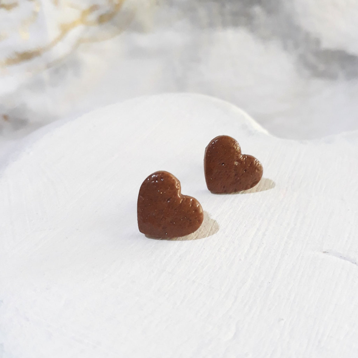Glossy brown heart-shaped polymer clay stud earrings with softly rounded edges.
