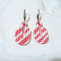 Bubblegum pink and white striped polymer clay earrings with stepped sides, rounded bases, elongated central cutouts and silver-tone ear hooks.