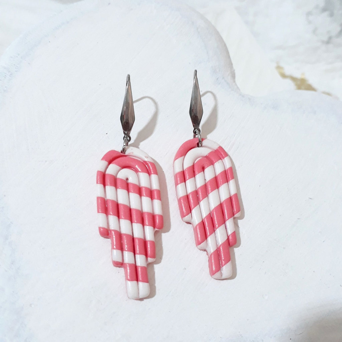 Bubblegum pink and white striped polymer clay stepped arch drops with glossy curved line detailing and elongated silver-tone ear hooks.