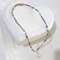  This handmade necklace pairs a white baroque freshwater pearl with eight small white rice pearls and colourful beads 