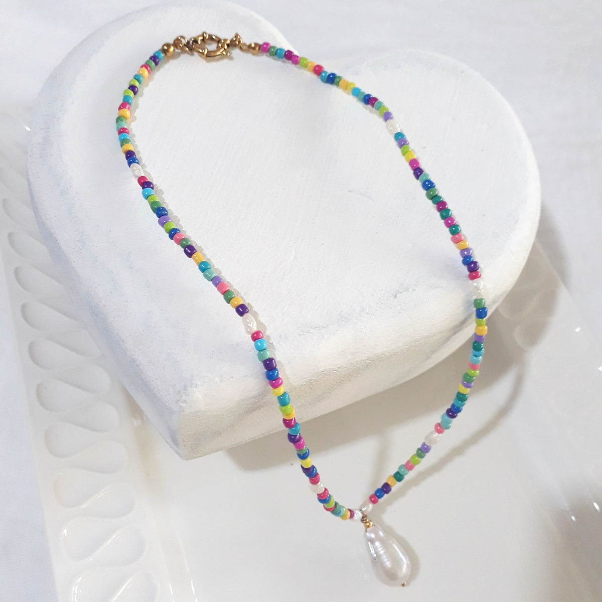  This handmade necklace pairs a white baroque freshwater pearl with eight small white rice pearls and colourful beads 
