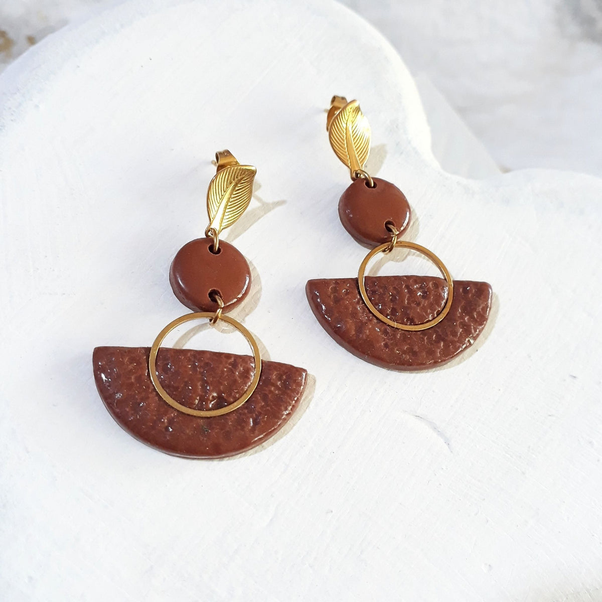 Brown polymer clay fan earrings with textured semicircle drops, round clay connectors, open gold-tone rings and leaf-shaped gold-tone studs.