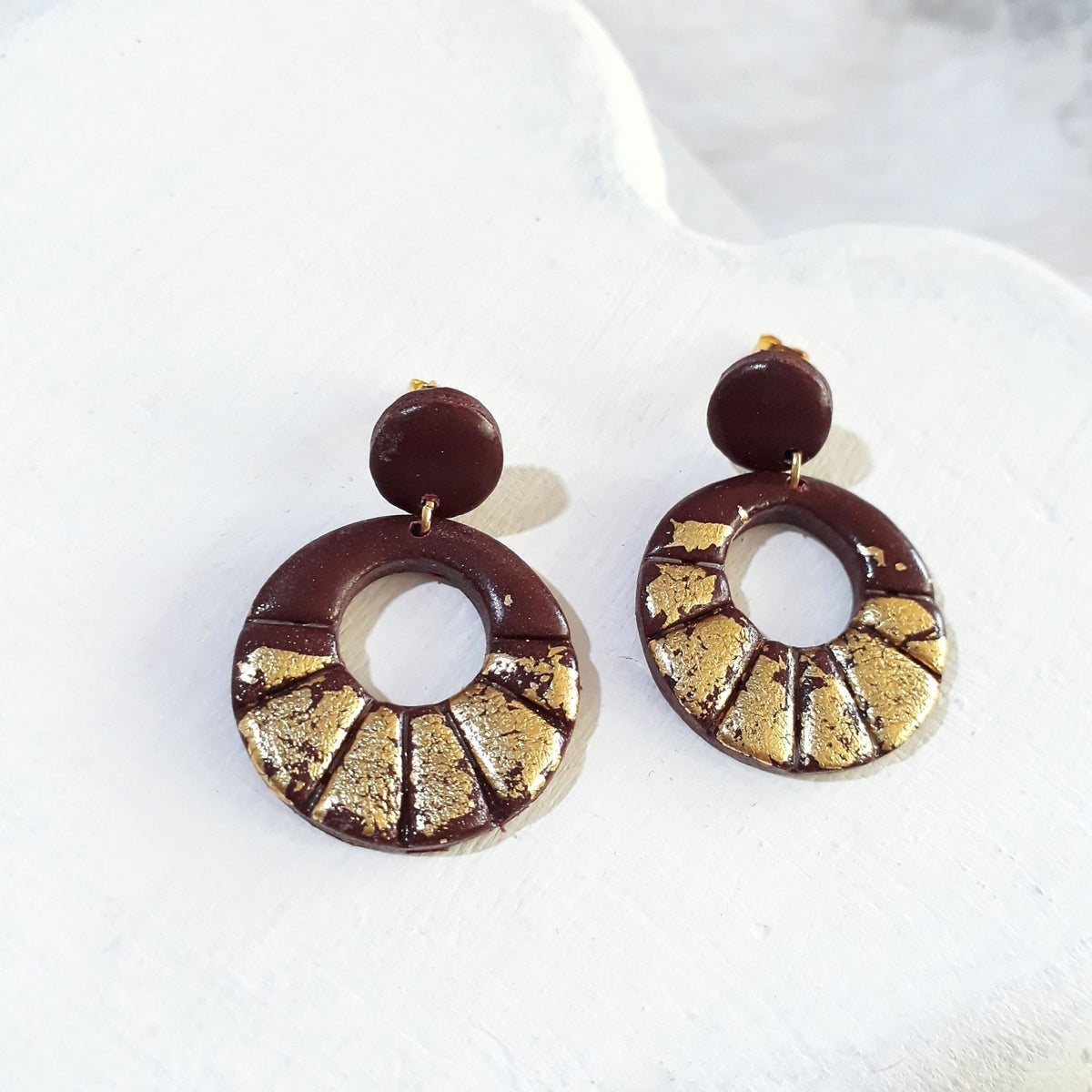 Dark-brown polymer clay earrings with round stud tops and grooved open-circle drops decorated with gold-coloured accents.