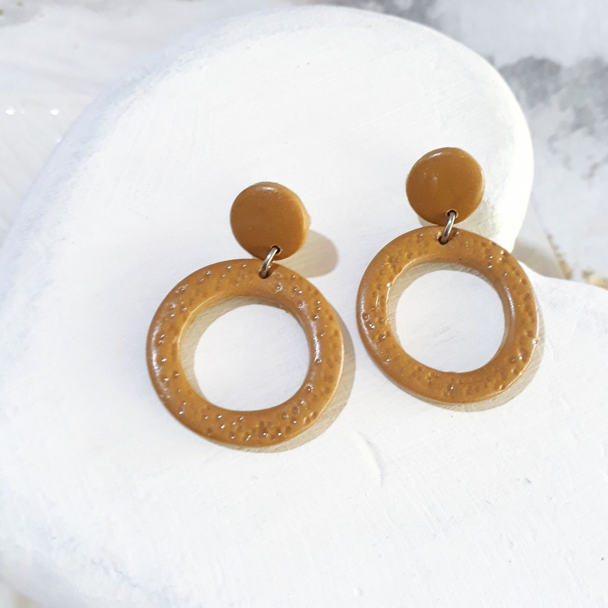 Golden ochre polymer clay earrings with smooth round stud tops and textured open-circle drops in a warm mustard-yellow shade.
