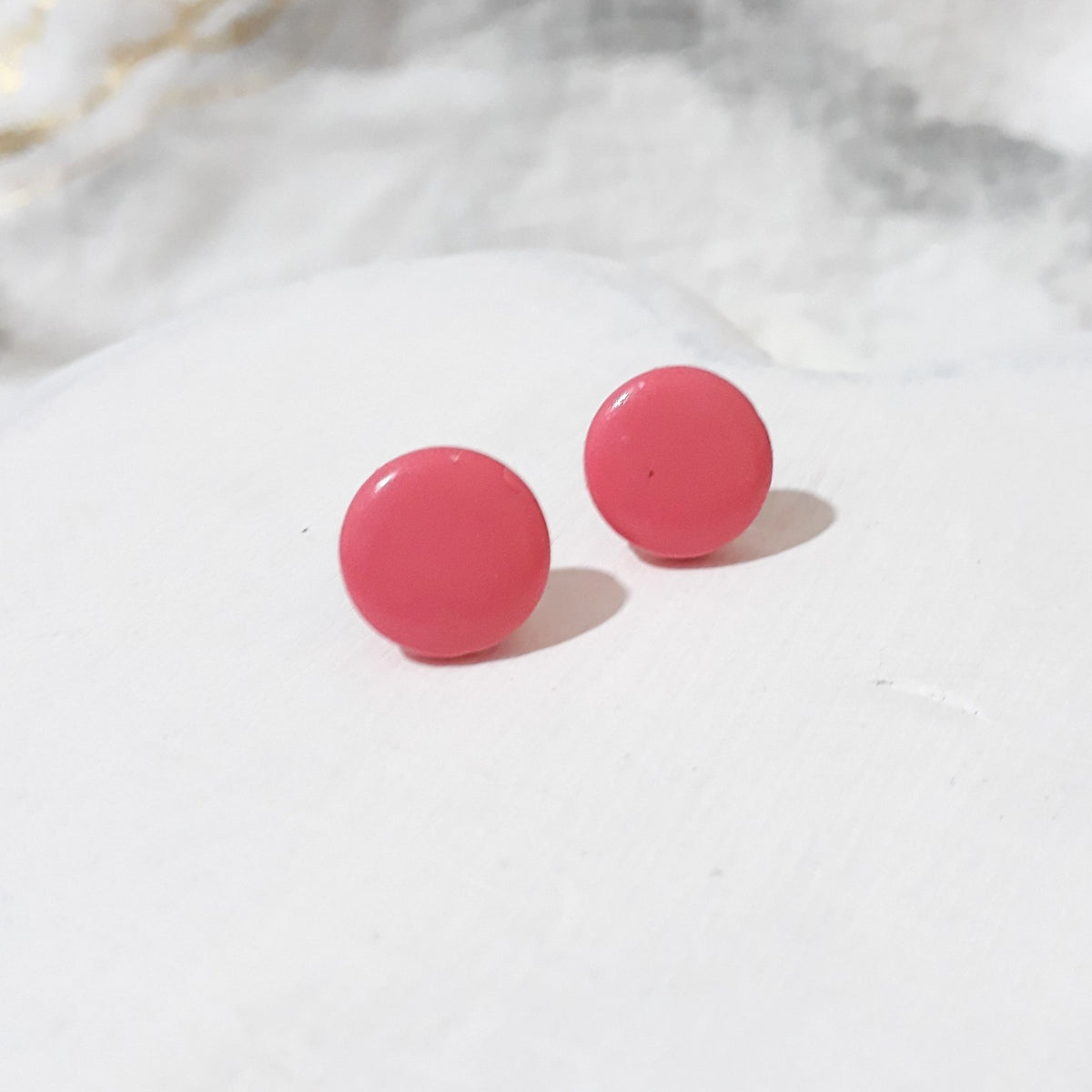 Pair of dark pink round polymer clay stud earrings with smooth glossy surfaces.
