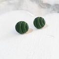 Deep green round polymer clay stud earrings with curved groove detailing and a glossy finish.