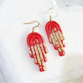 Glossy deep-orange polymer clay stepped arch drop earrings with gold-coloured accents and gold-tone shepherd ear hooks.
