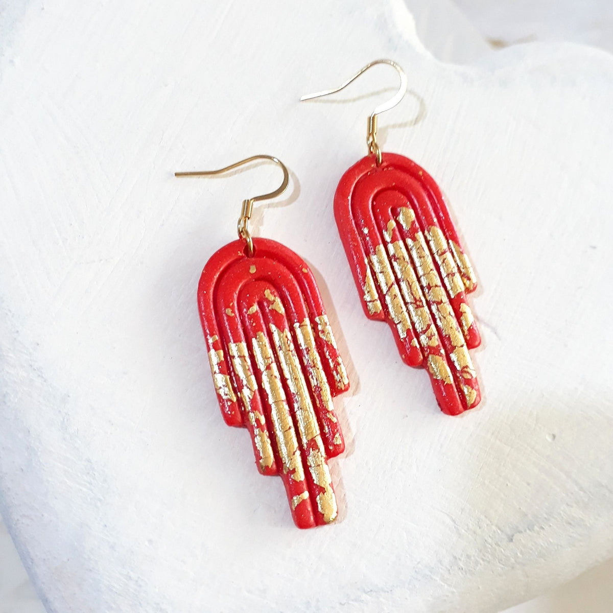 Glossy deep-orange polymer clay stepped arch drop earrings with gold-coloured accents and gold-tone shepherd ear hooks.