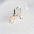 Double freshwater pearl drop earrings with peach-pink pearls above white pearls on silver-tone elegant ear hooks.