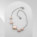 Handmade stainless steel bracelet featuring a peach-pink freshwater coin pearl with two matching freshwater pearls on a cable chain.