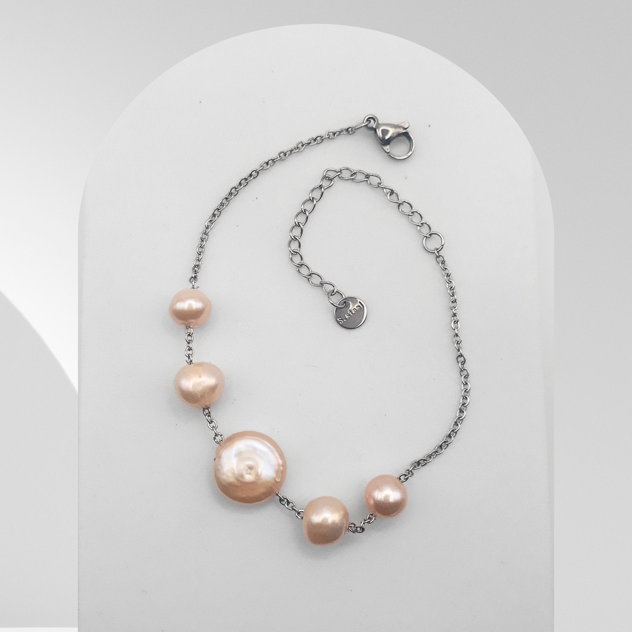 Handmade stainless steel bracelet featuring a peach-pink freshwater coin pearl with two matching freshwater pearls on a cable chain.