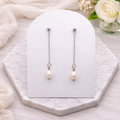 Dainty dangle Pearl earrings on a white card with flowers in the background