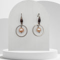 Pair of earrings with pink pearls on a white stand