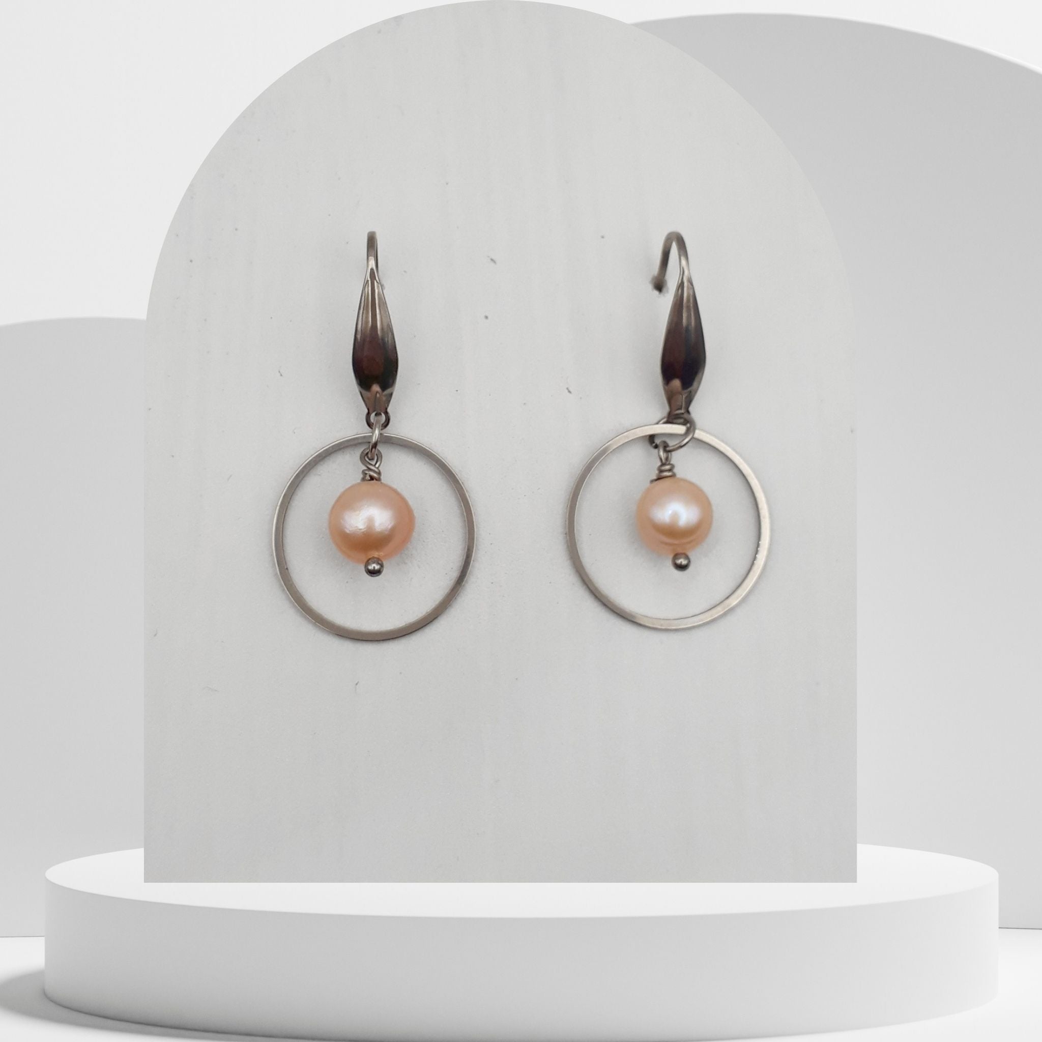 Pair of earrings with pink pearls on a white stand