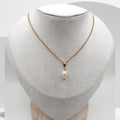 Gold necklace with a pearl pendant on a mannequin bust.