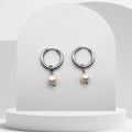 Silver hoop earrings with pearl drops on a white pedestal