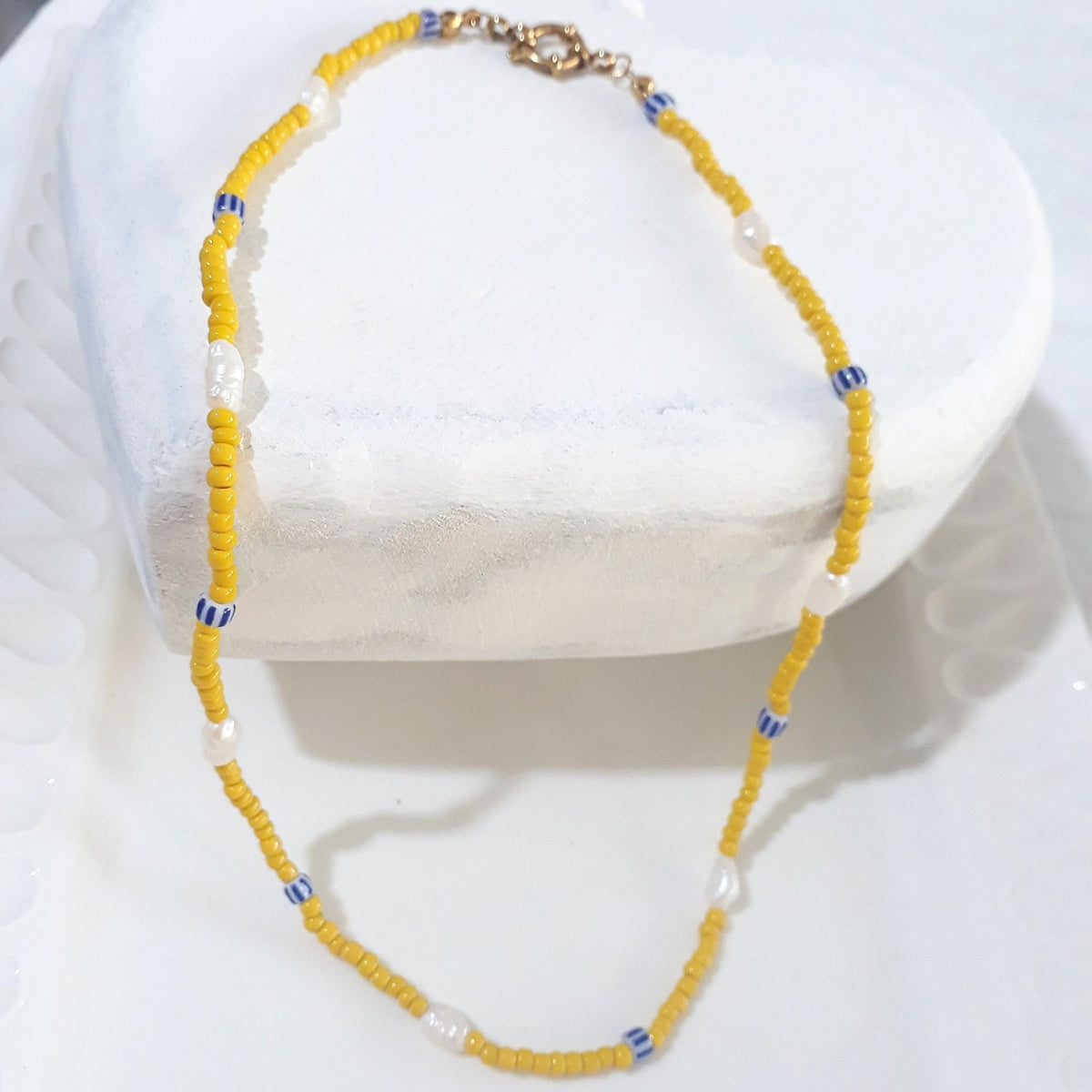 This handmade necklace pairs seven white freshwater rice pearls with yellow glass beads and small blue-and-white ceramic beads