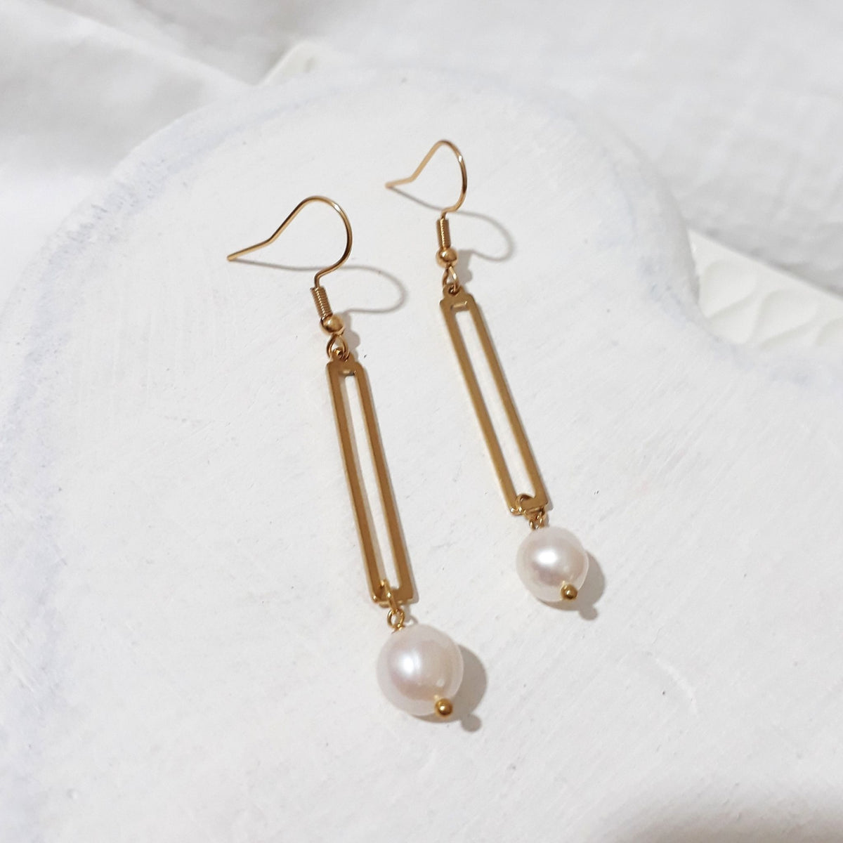 Gold-tone open rectangular bar earrings with white freshwater pearl drops and shepherd ear hooks.