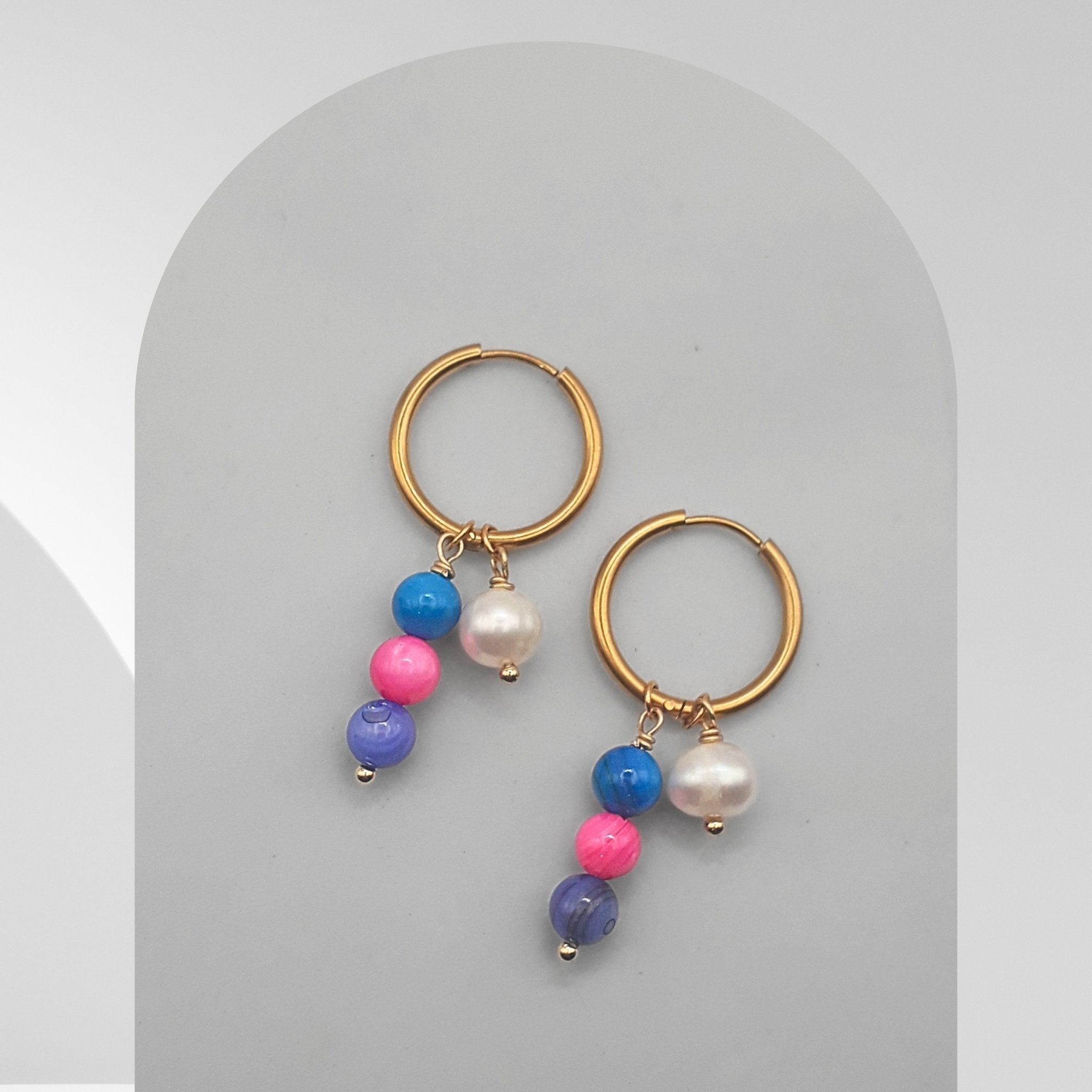 Gold hoop earrings with colorful beads on a gray background