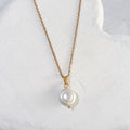 White freshwater coin pearl pendant with a softly uneven lustrous surface on a gold-tone chain and bail.