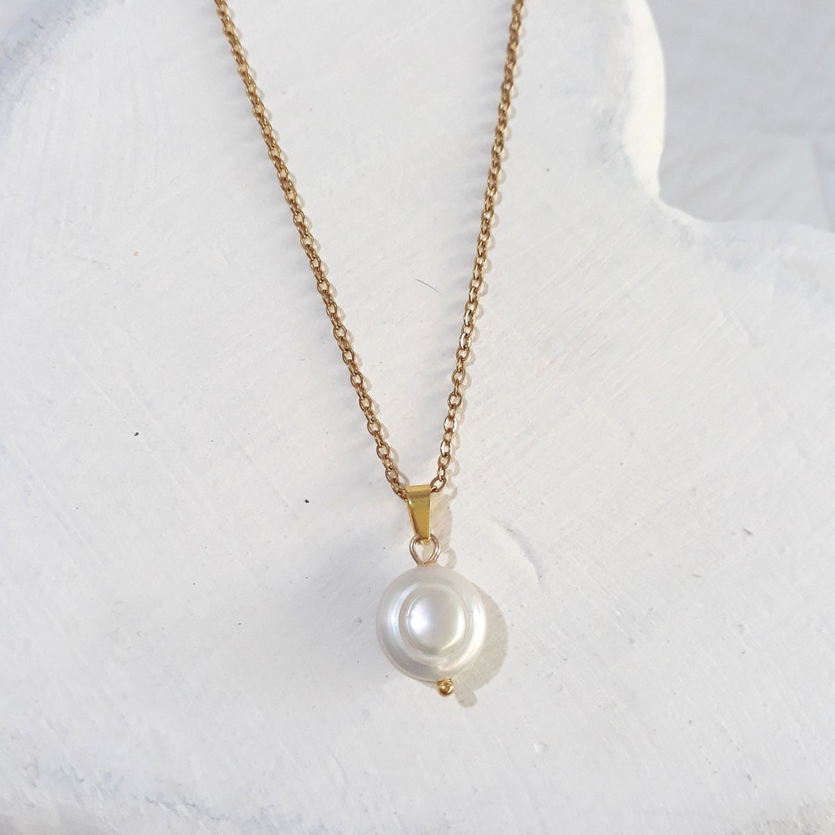 White freshwater coin pearl pendant with a softly uneven lustrous surface on a gold-tone chain and bail.