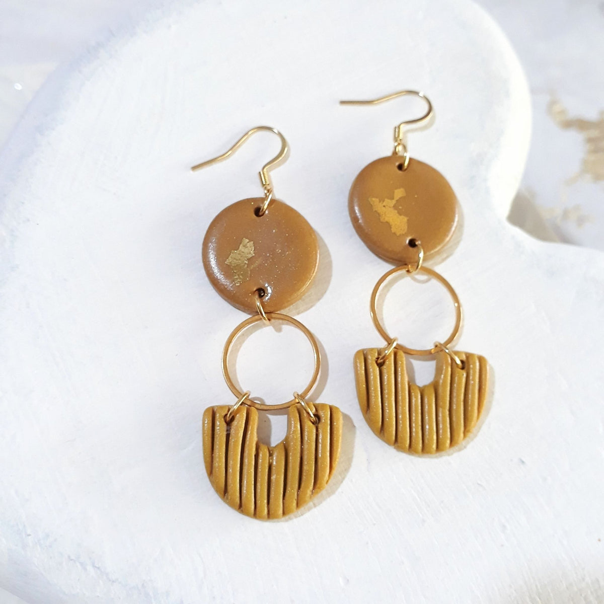 Golden ochre round polymer clay tops with gold-coloured accents, gold-tone ring connectors and ridged mustard semicircle drops on shepherd hooks.