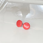 Handmade 14mm salmon pink polymer clay stud earrings on white display tray