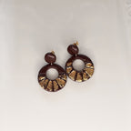 A pair of handmade polymer clay earrings featuring dark brown circular discs with a textured gold leaf pattern along the bottom edge, suspended from small dark brown beads on a plain white background.
