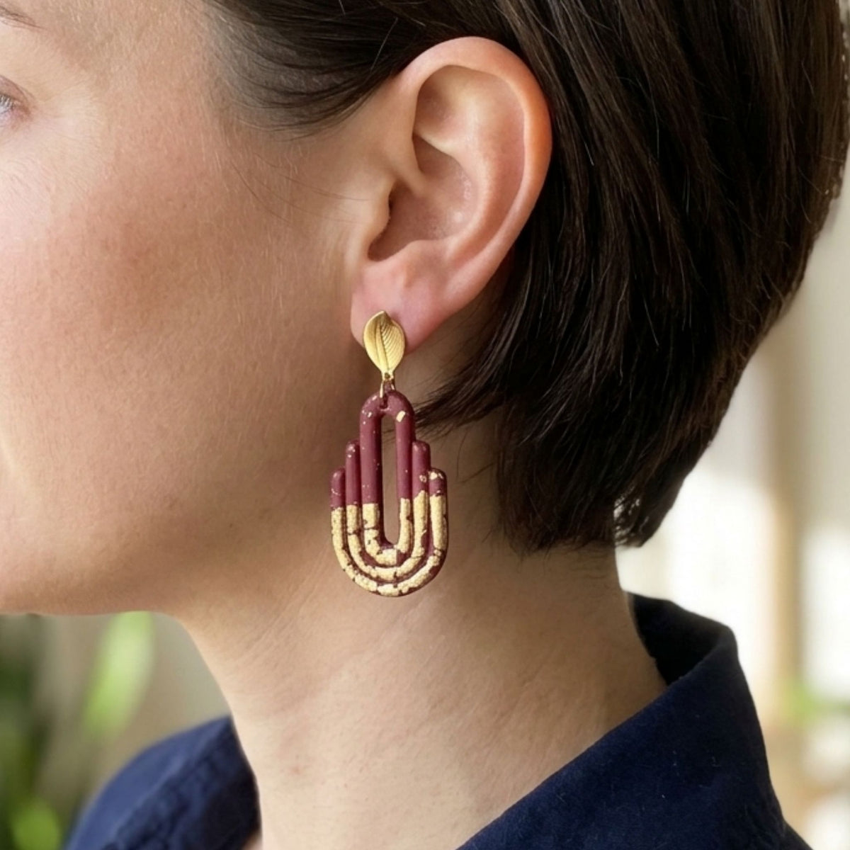 Handmade dark maroon and gold Art Deco arch polymer clay earrings - worn lifestyle shot
