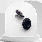 Black earrings on a white stand with a gray background