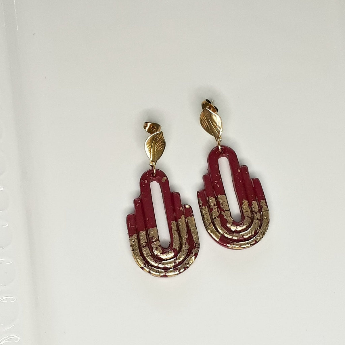 Handmade dark maroon and gold Art Deco arch polymer clay earrings - flat lay product view