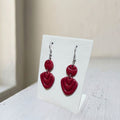 Handmade dark maroon layered teardrop polymer clay dangle earrings on white display stand