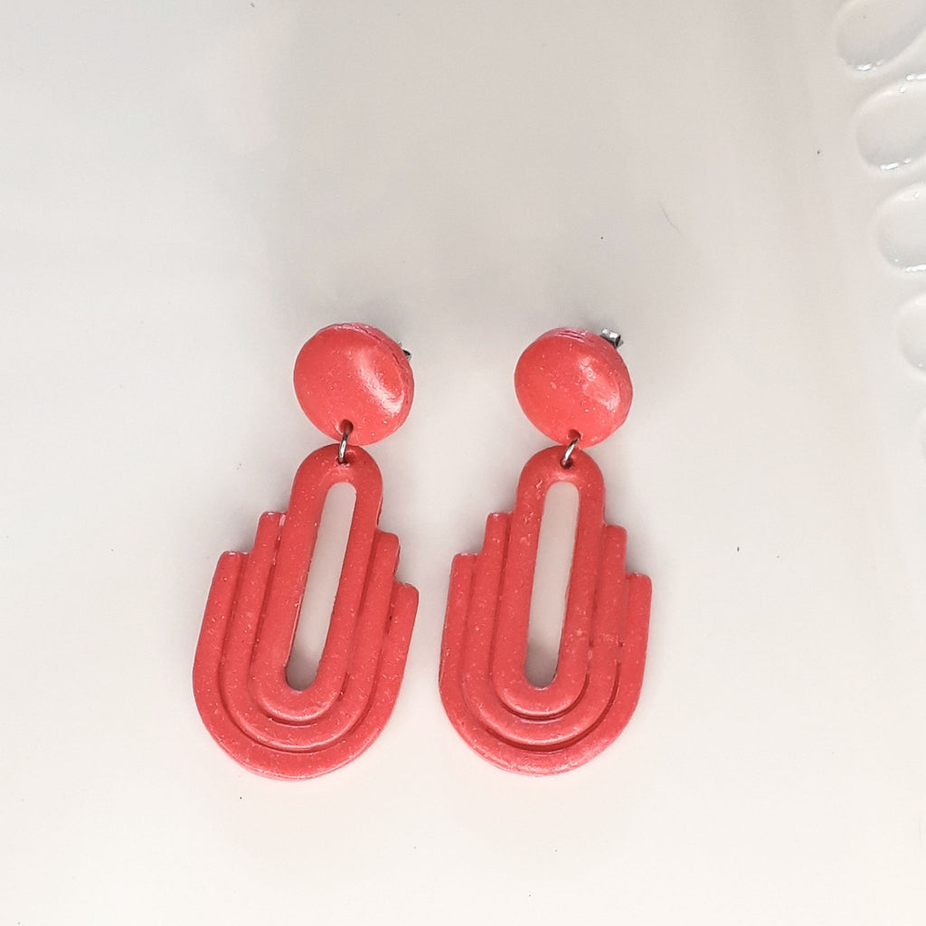 Handmade salmon pink Art Deco arch cutout polymer clay drop earrings on white display tray